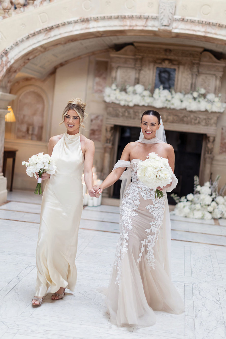 Two women holding hands and holding flowers.