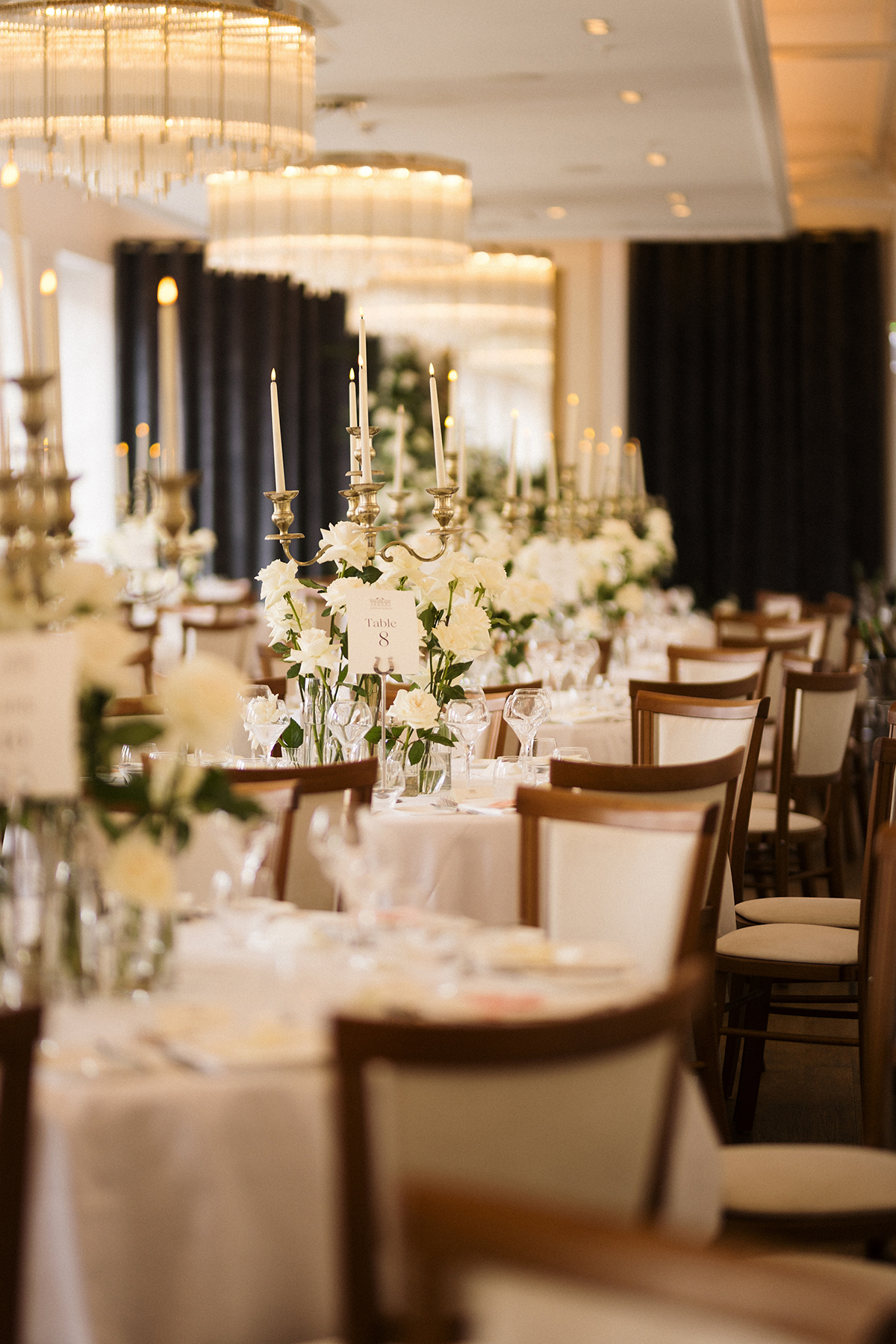 Elegant wedding reception tables with white flowers, candelabras and chandeliers