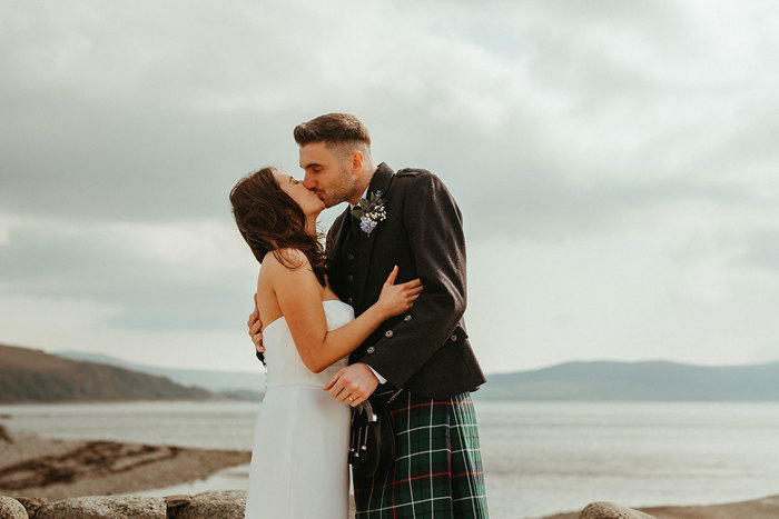 bride and groom kiss with sea and sand in the background during wedding at dougarie boathouse