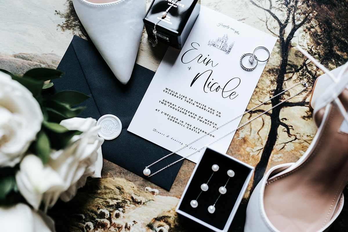 Wedding stationery flat lay featuring invitation, rings, pearl jewellery and bridal accessories at Cornhill Castle