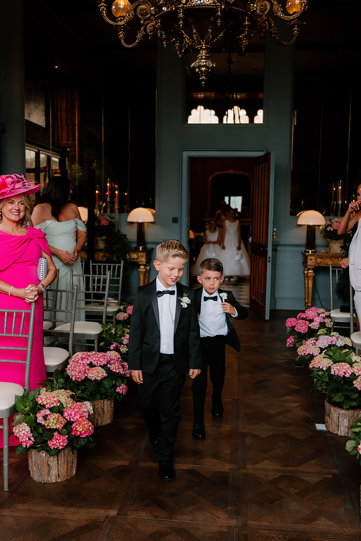 Two page boys walking down the aisle at the Mar Hall ceremony, surrounded by floral arrangements.