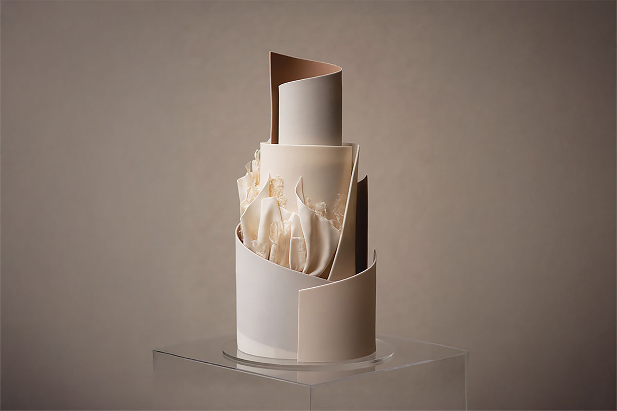 Sleek minimalist wedding cake with artistic modern design featuring curved white panels and delicate sugar detailing, created by YiShi Cake in Edinburgh