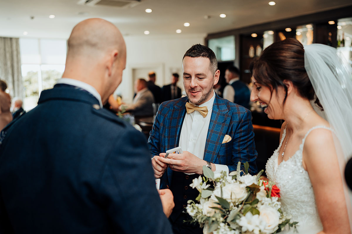 Magician Billy Reid performing a card trick for a bride and groom at Seamill Hydro