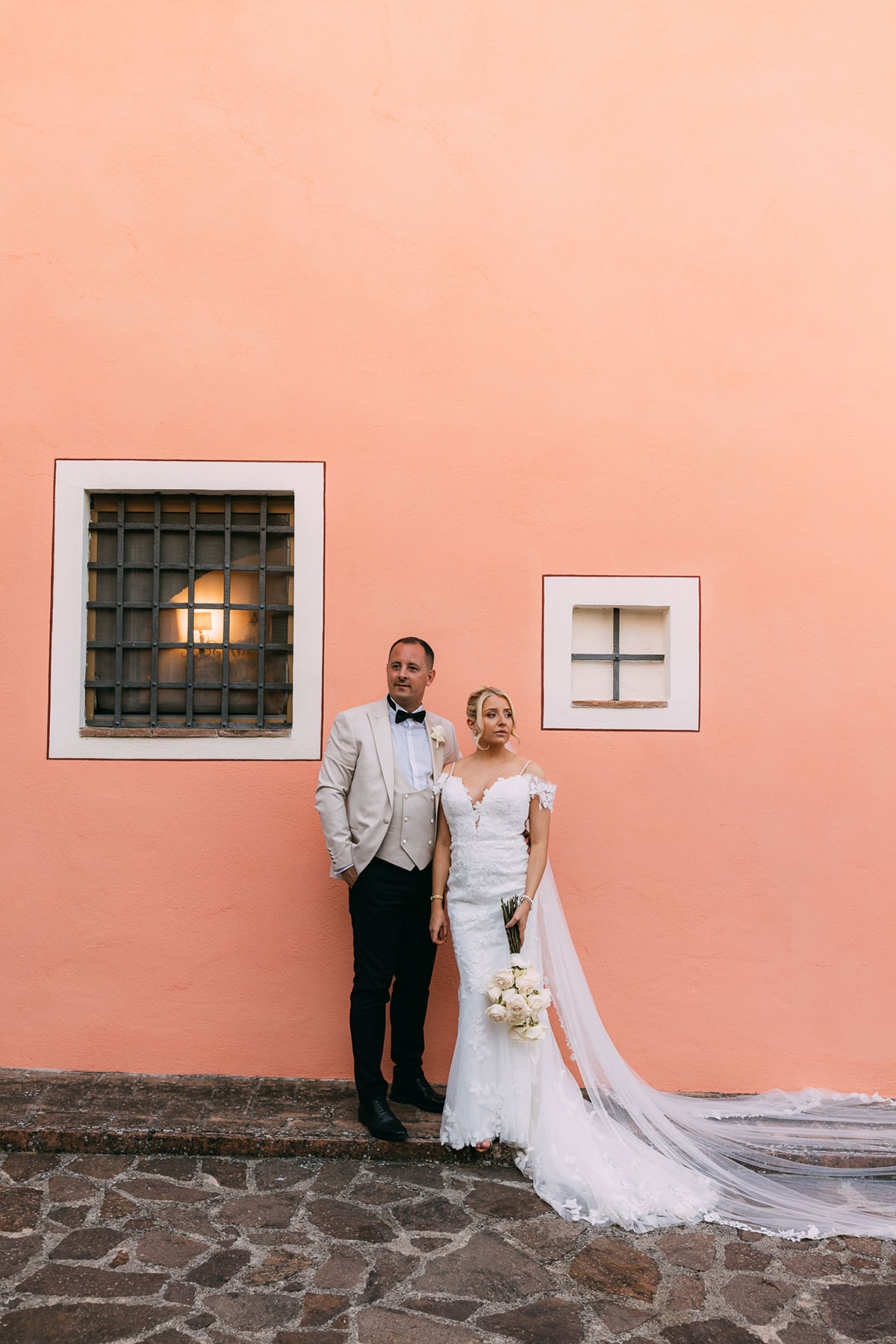 Bride and groom portrait against pastel pink wall at Antico Borgo San Lorenzo Tuscany wedding