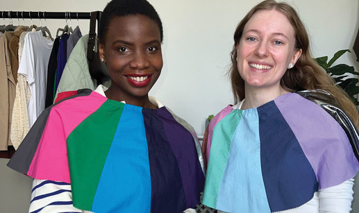 two women sit side by side with differently coloured fabric draped across their shoulders for comparison 