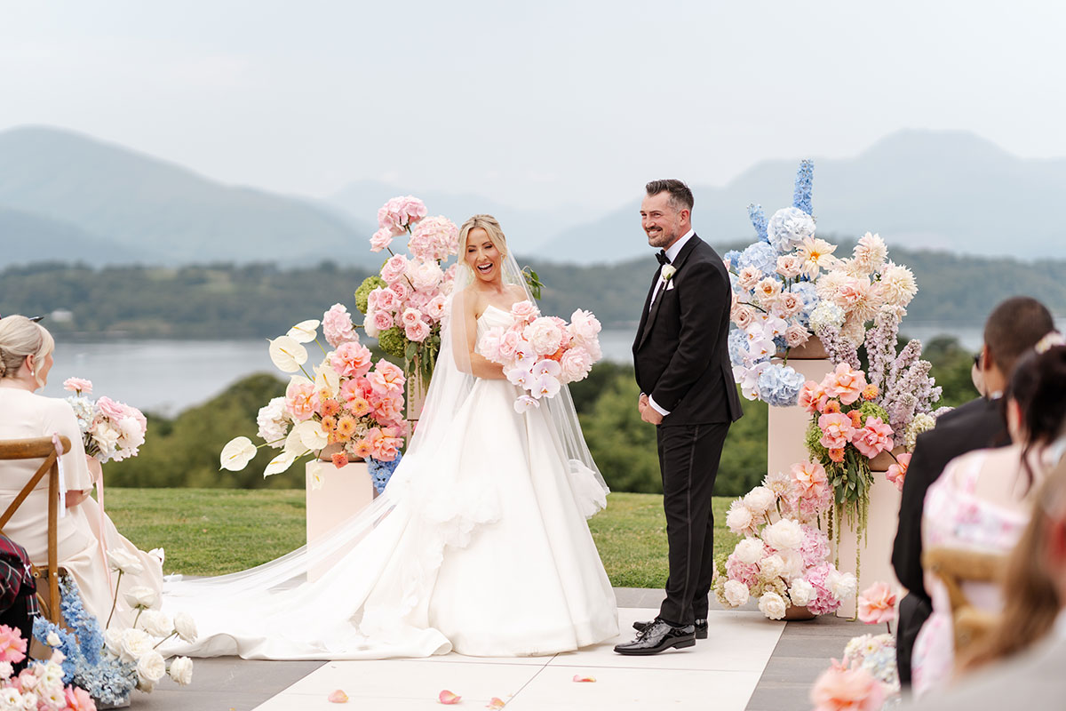 Outdoor wedding ceremony at Boturich Castle with floral installations overlooking Loch Lomond and the surrounding Scottish hills.
