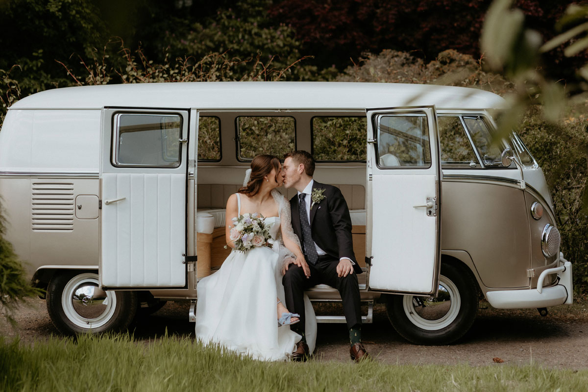 Newlyweds kissing while sitting in the doorway of a vintage campervan at The Byre at Inchyra.