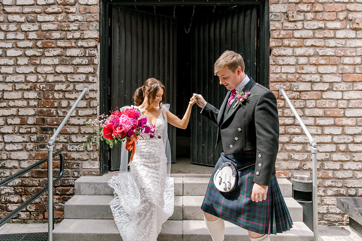 Bride and groom walking hand in hand down the steps outside their wedding venue