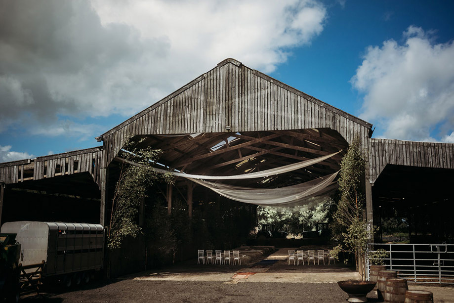 A Shed On Boswells Estate Dressed For A Wedding with white drapes from ceiling and haybales