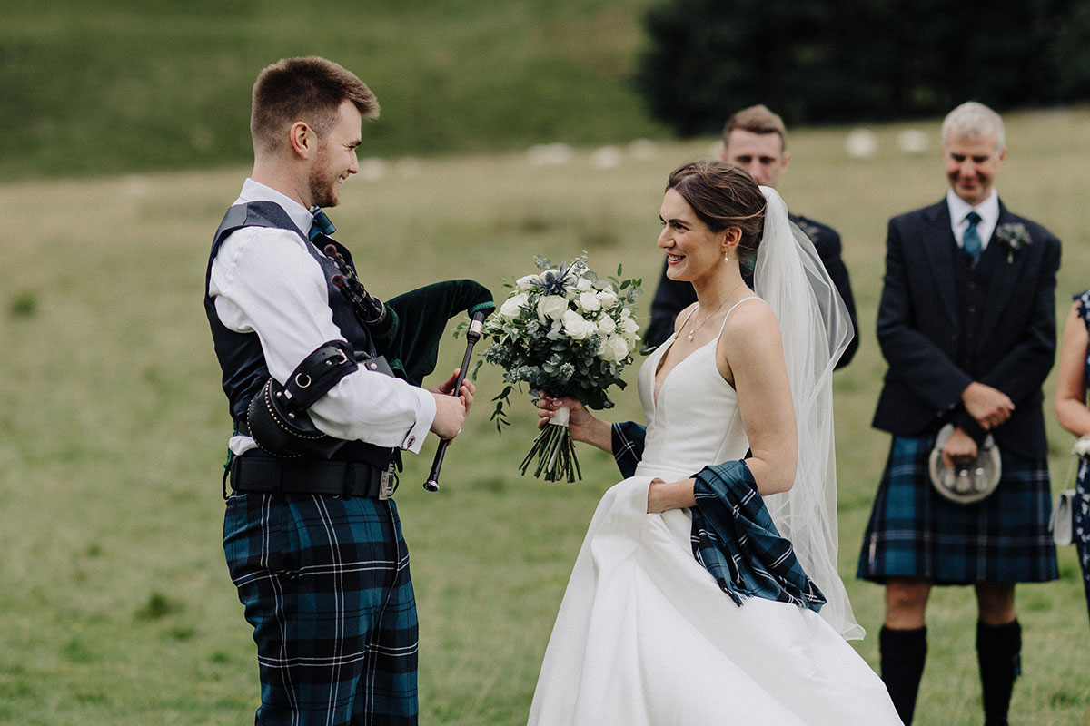 Groom playing the pipes as bride walks to him