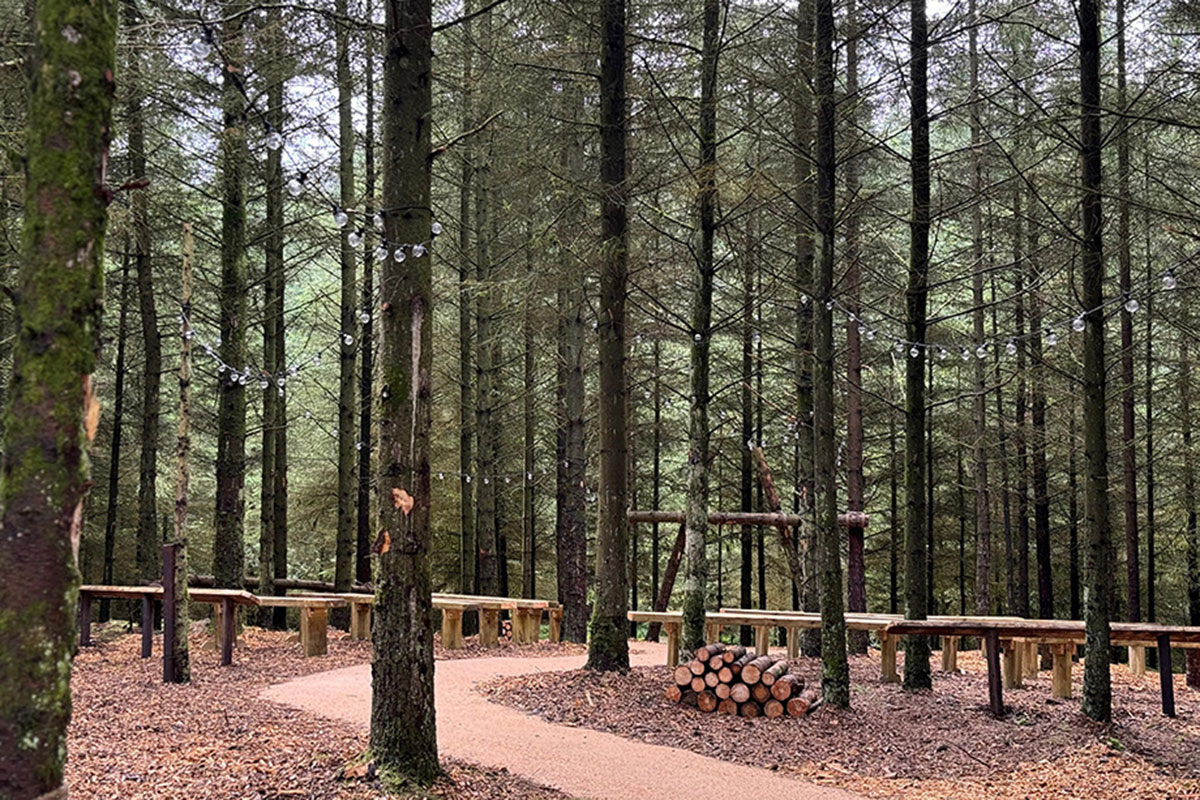 Woodland wedding ceremony area at Eden Leisure Village with wooden benches set among forest trees.