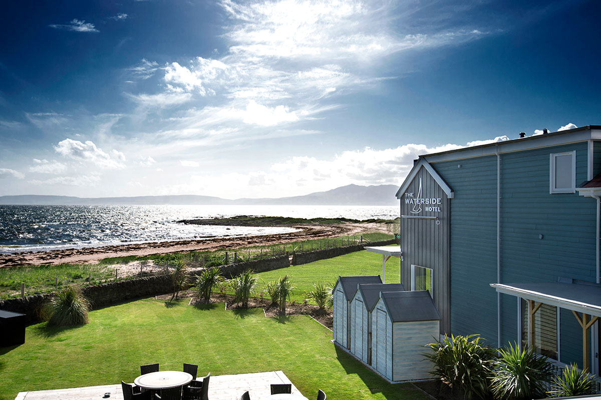 Exterior view of The Waterside Hotel overlooking the coastline and landscaped gardens.