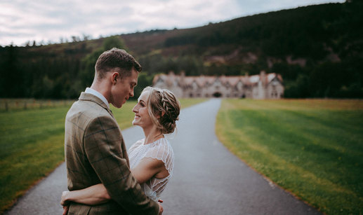 bride and groom look at one another with mar lodge in background