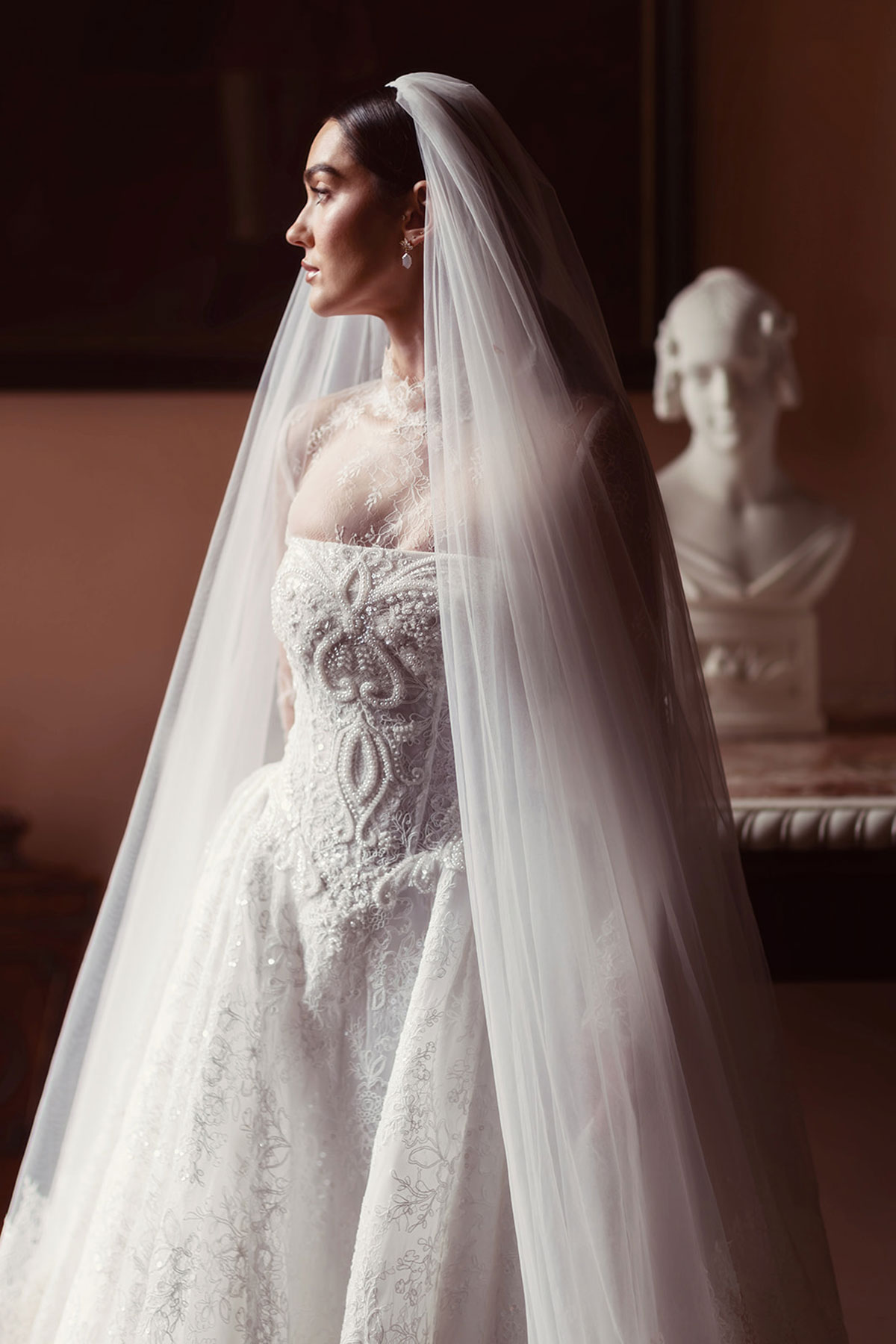 Lace wedding dress with a long train styled in dramatic light inside Gosford House.