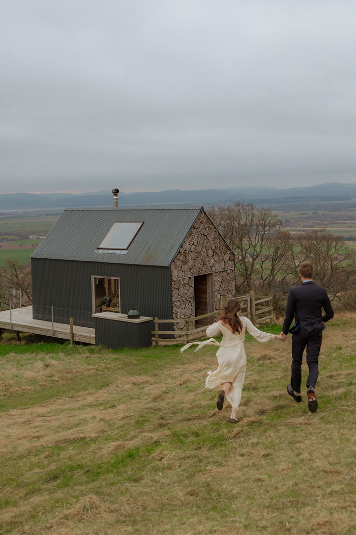 couple running towards timber hut at guardswell farm