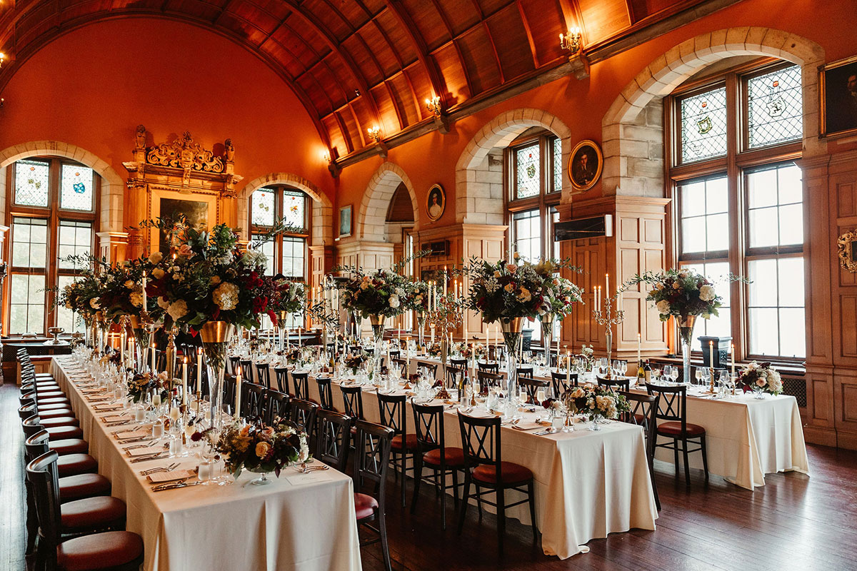 Elegant wedding reception at Barnbougle Castle with long banquet tables, dramatic floral centrepieces, candlelight and historic wood-panelled interiors