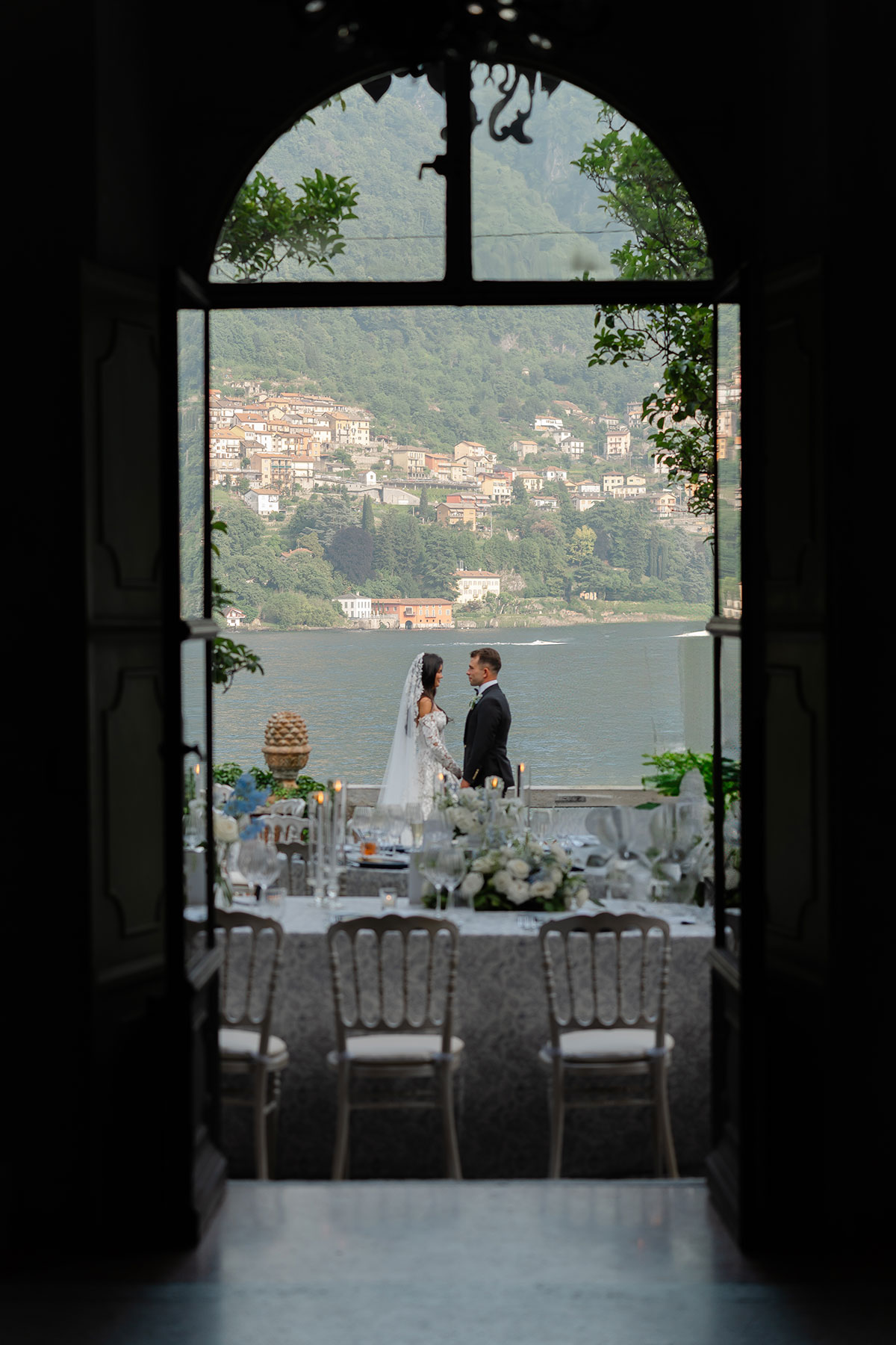 Bride and groom standing together at Villa Regina Teodolinda, overlooking Lake Como during their destination wedding.