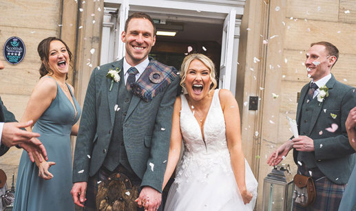 bride and groom hold hands and smile from ear to ear during their confetti toss