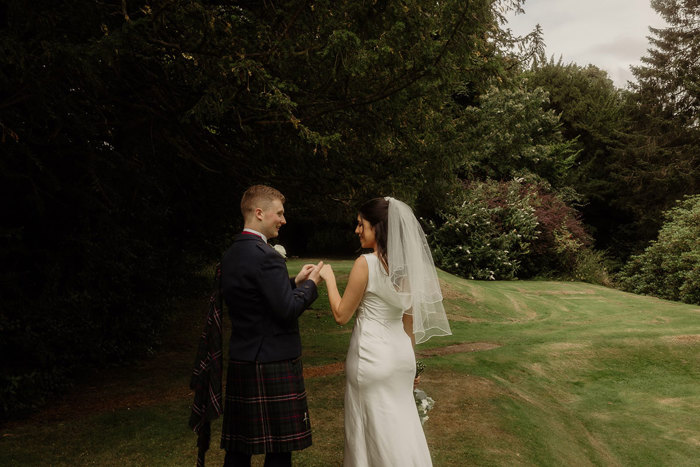 bride and groom walk through the gardens at kilmardinny house in bearsden