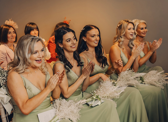 girls sitting on chairs in green dresses clapping