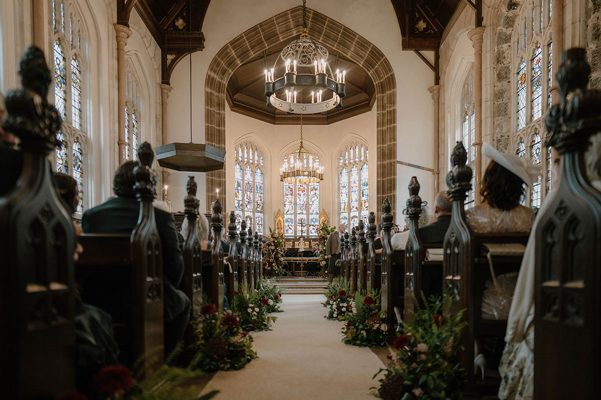 Interior of Cluny Castle’s chapel with stained glass windows set up for a Scottish castle wedding ceremony.