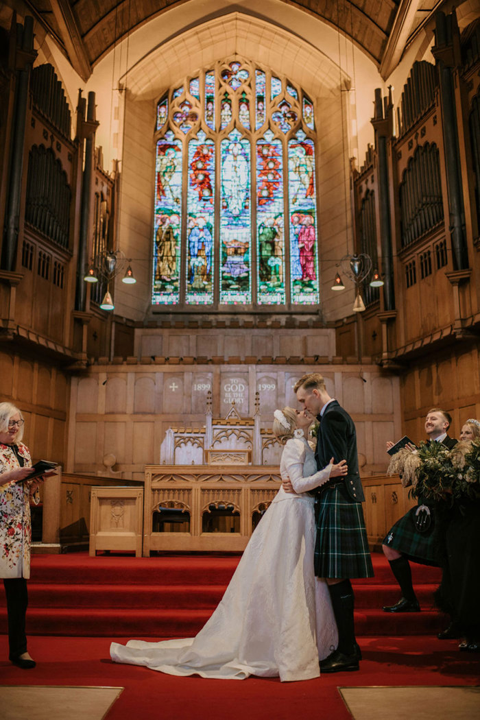 a bride and groom standing in a church kissing