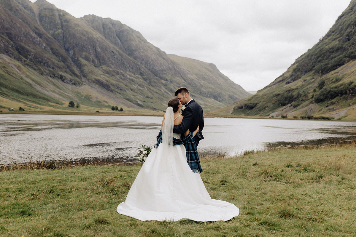 Bride and groom sharing a kiss by the water