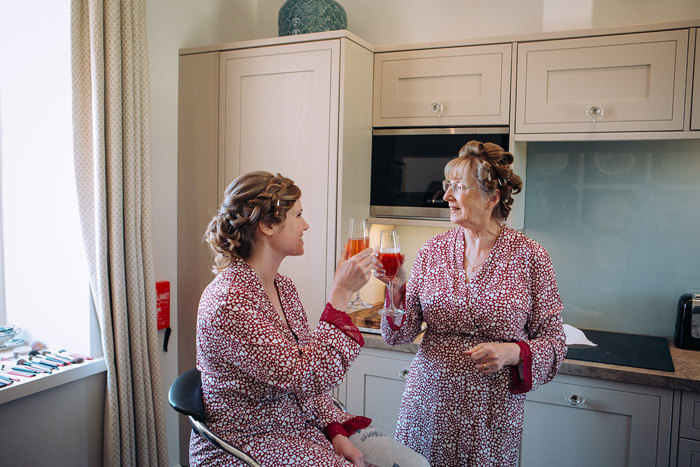 Bride and her mother toasting glasses, wearing red and white love heart print dressing gowns
