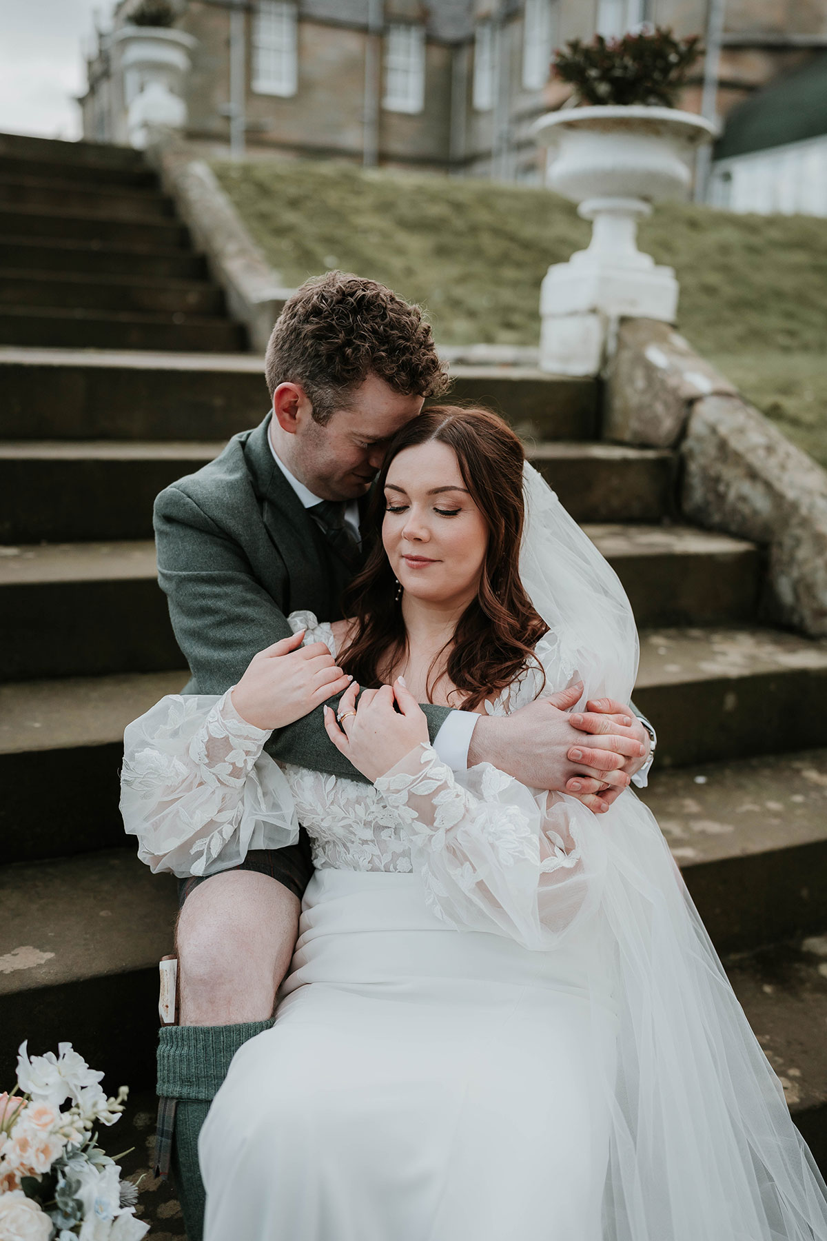 Bride and groom seated closely on outdoor steps