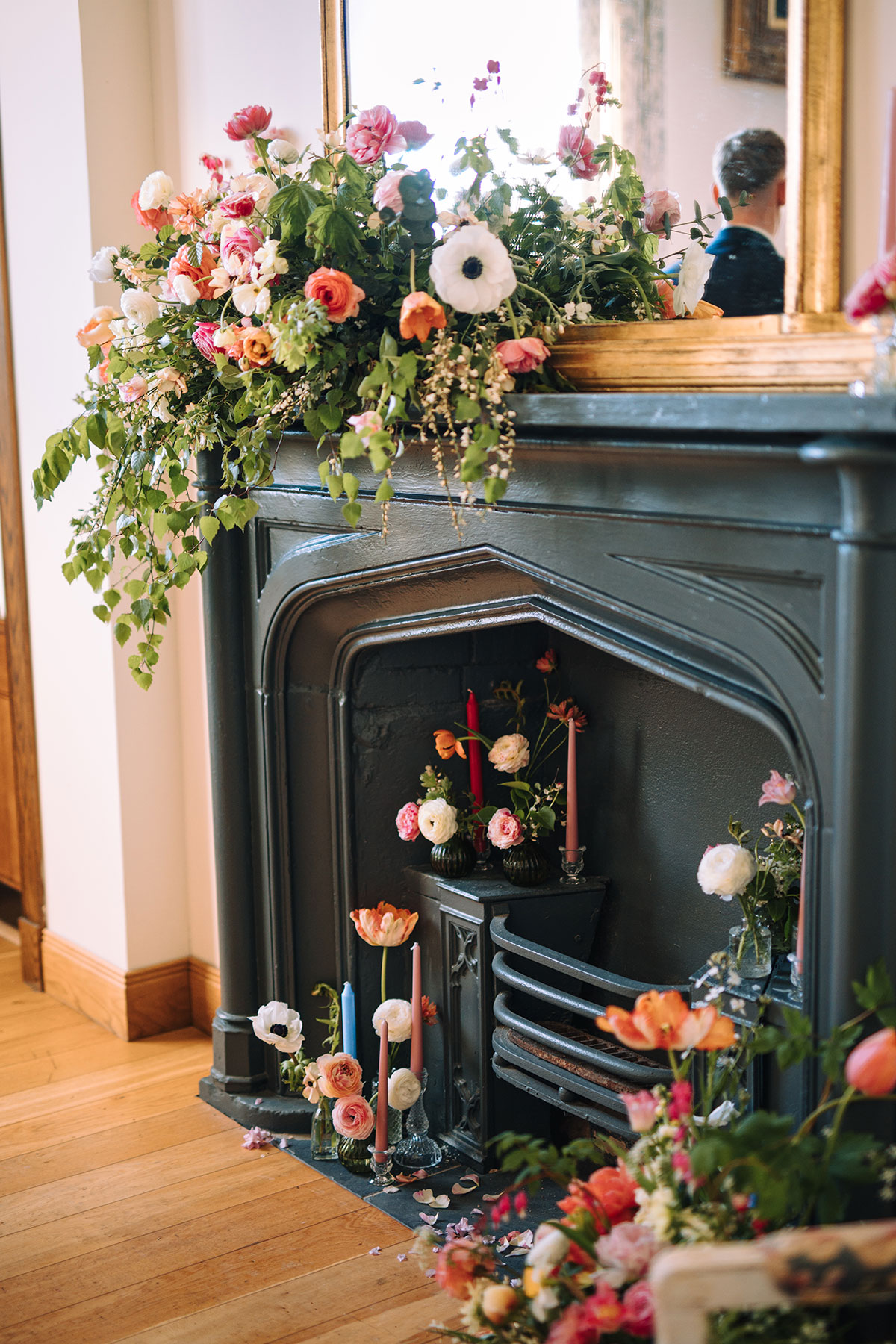 Fireplace decorated with colourful wedding florals and candles in elegant indoor ceremony space