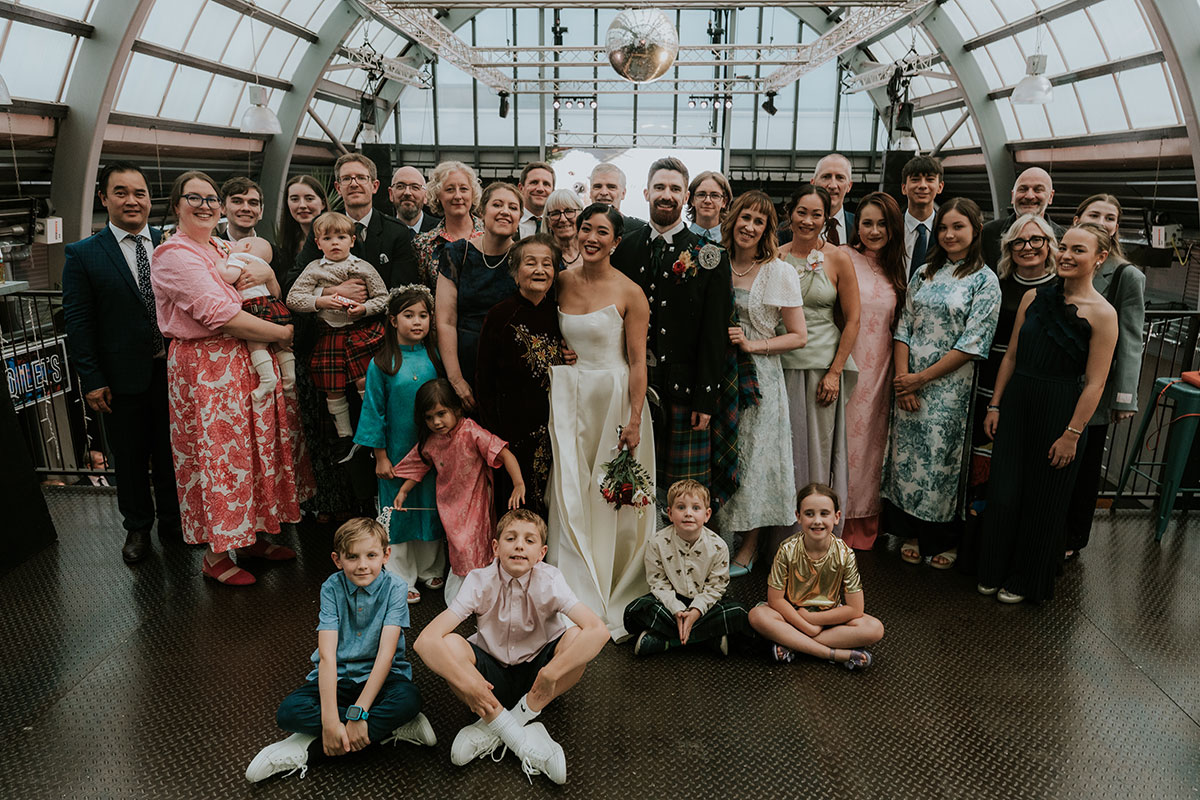 Wedding family group photo on balcony inside Barras Art and Design Glasgow with couple centred