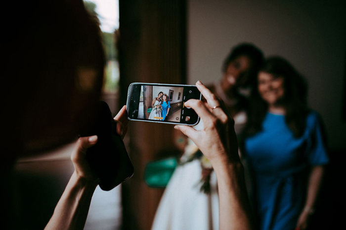Photo showing a phone taking a picture of bride and guest