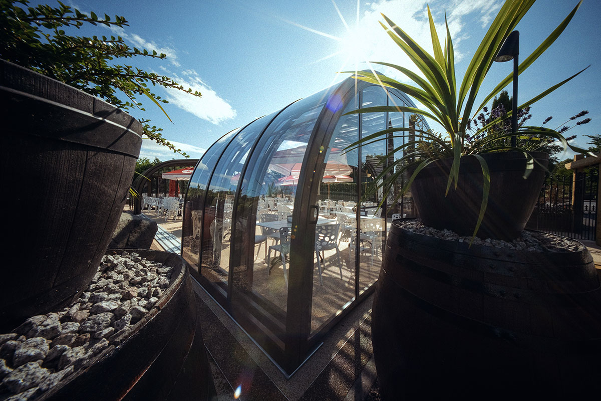 Riverside Glasshouse at The River Inn in Renfrewshire, with curved glass walls and outdoor seating in the sunshine.