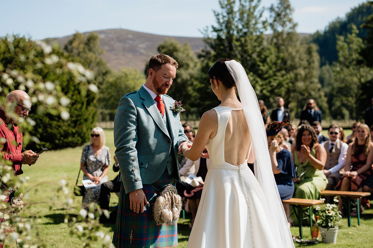 Bride and groom exchanging rings during an outdoor wedding ceremony at Mar Lodge Estate in the Scottish Highlands