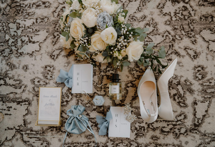 flat lay of wedding items including invitation, shoes and perfume