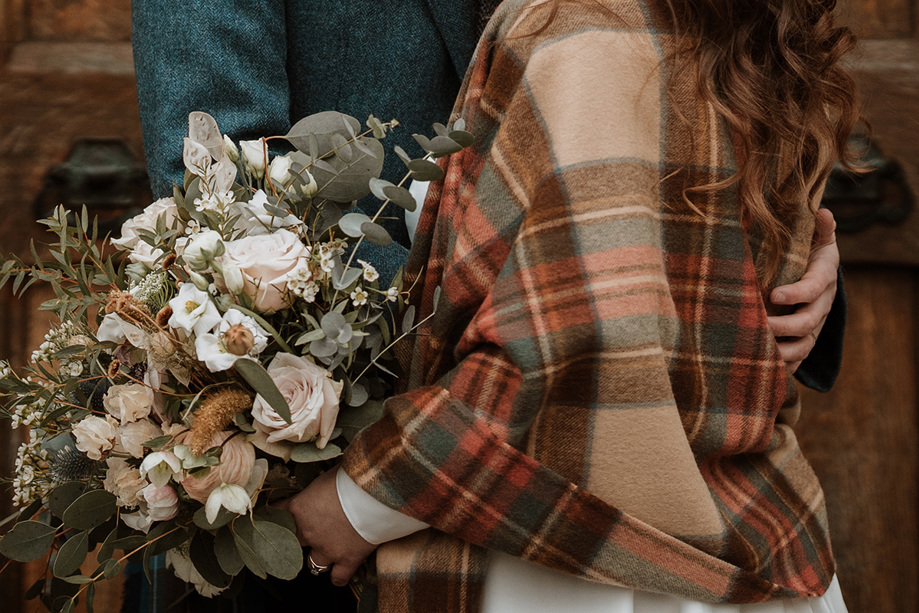 Bride with tartan shawl on holding neutral coloured bouquet