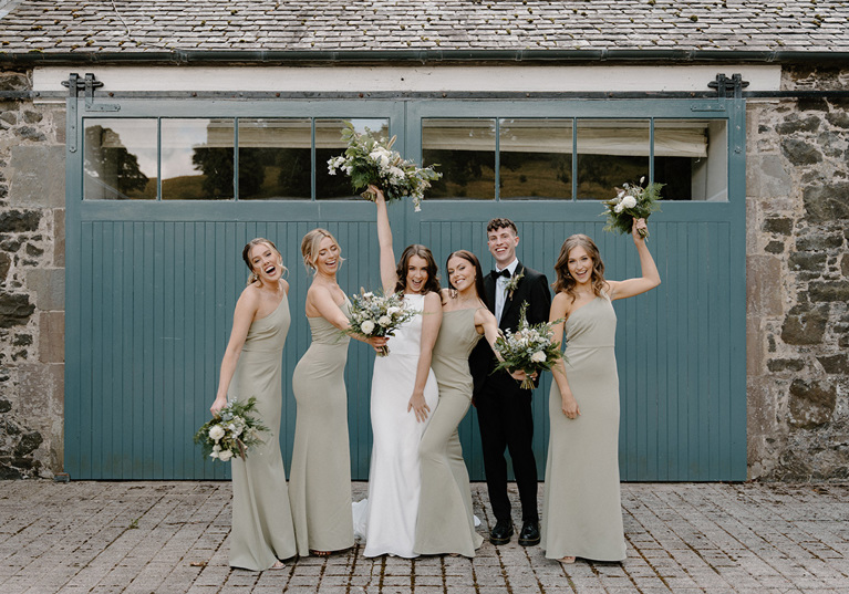 Bride, groom and bridesmaids smiling with their bouquets