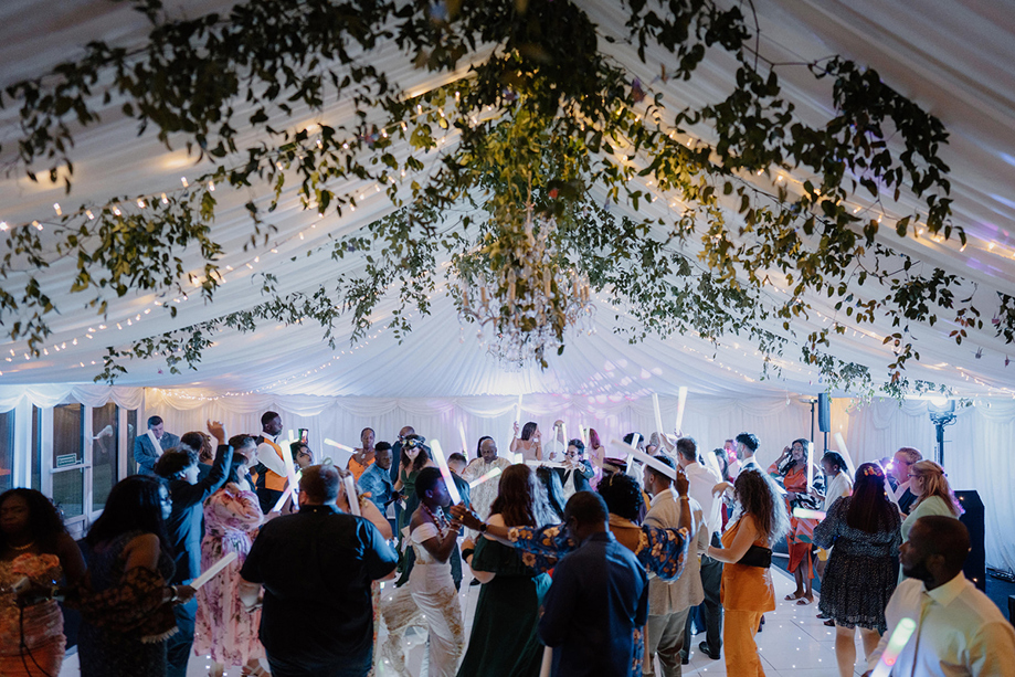 Guests dancing under a wedding marquee with hanging foliage and fairy lights at an outdoor Scottish wedding reception