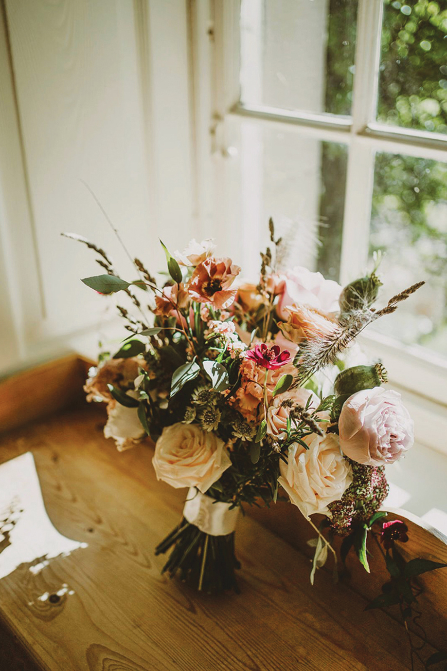 Romantic bridal bouquet with roses and peonies styled on a windowsill in natural light