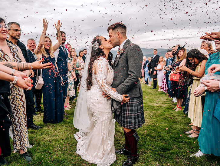Newlyweds kiss during an outdoor confetti throw at a Scottish wedding planned by Pebblefish Occasions & Events.