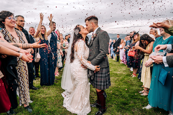 Newlyweds kiss during an outdoor confetti throw at a Scottish wedding planned by Pebblefish Occasions & Events.