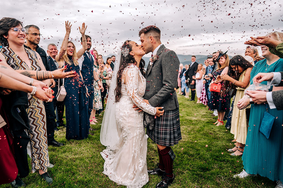 Newlyweds kiss during an outdoor confetti throw at a Scottish wedding planned by Pebblefish Occasions & Events.