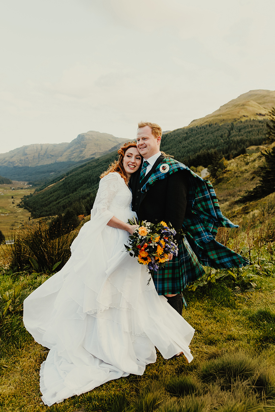 Bride and groom in Scottish wedding attire posing in a Highland landscape at a wedding planned by Pebblefish Occasions & Events.