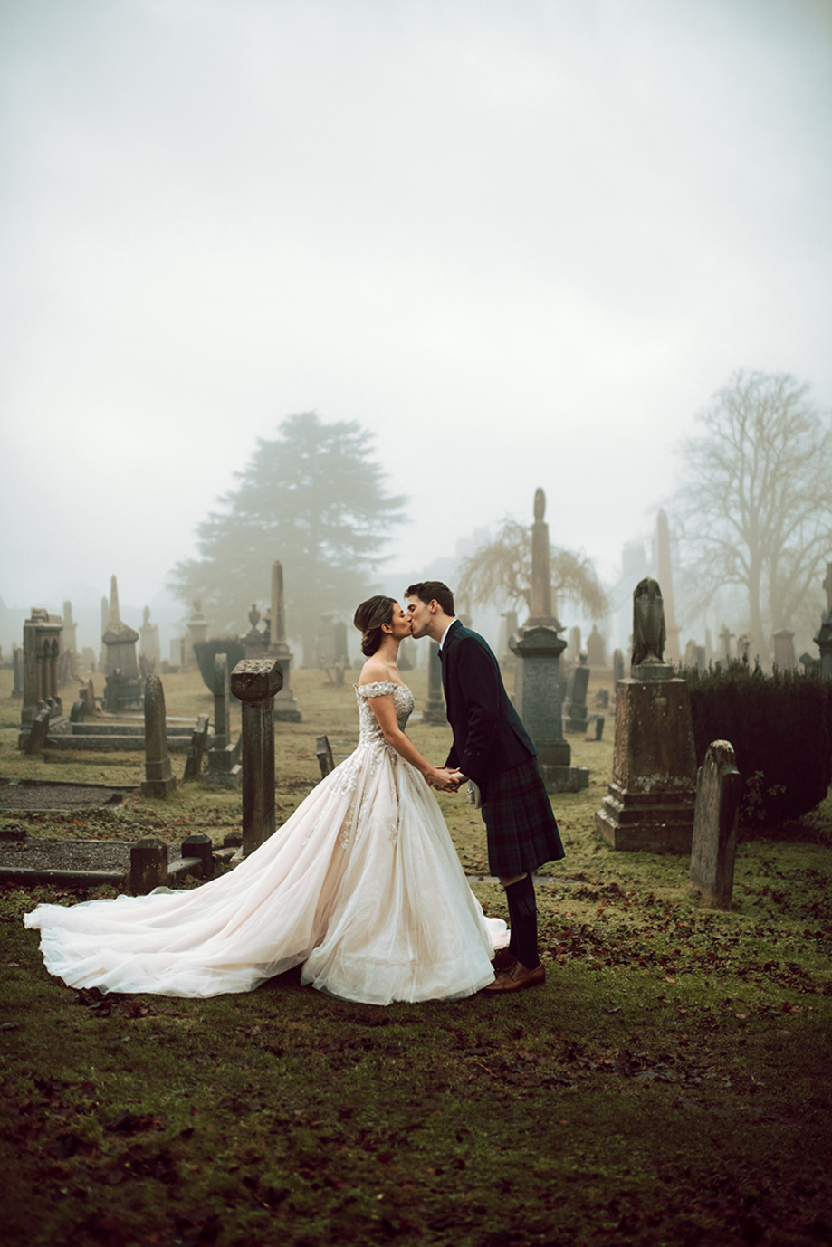 Bride and groom kissing in a misty historic graveyard during a Scottish wedding planned by Pebblefish Occasions & Events.