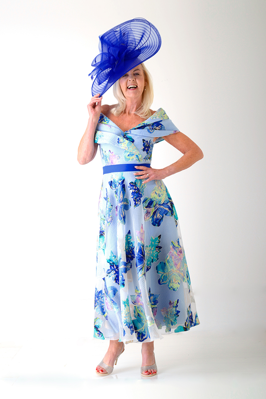 Blue floral off-shoulder occasion dress with oversized royal blue hat
