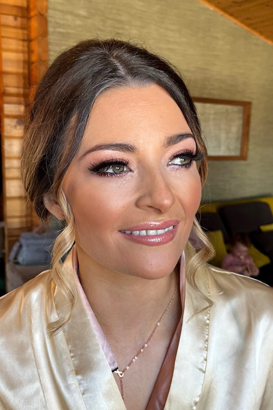 Bride with pink lipgloss, coral blush and false eyelashes on with curled money pieces