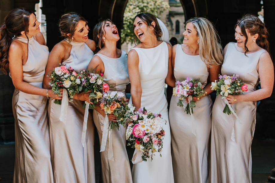 Bride and her bridesmaids laughing with bouquets in hand