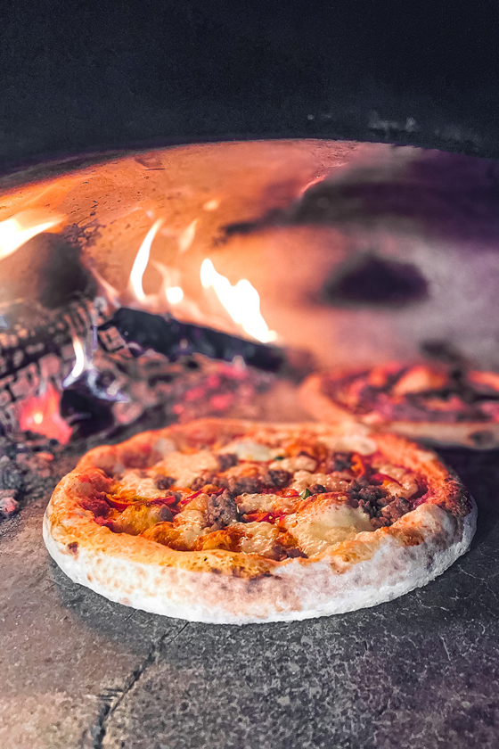 Image of pizza cooking in Dough Man's Land pizza oven