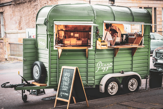 Green Dough Man's Land horsebox on street with blackboard stand