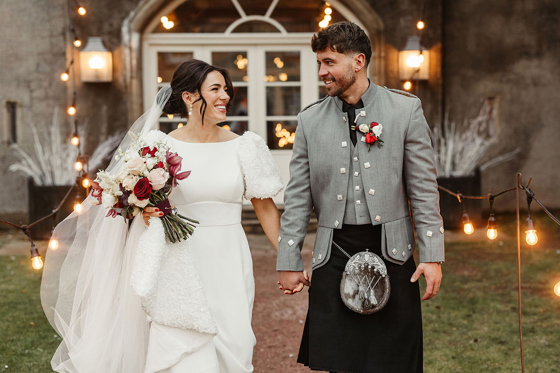 Bride and groom smile as they walk away from Gordon Castle.